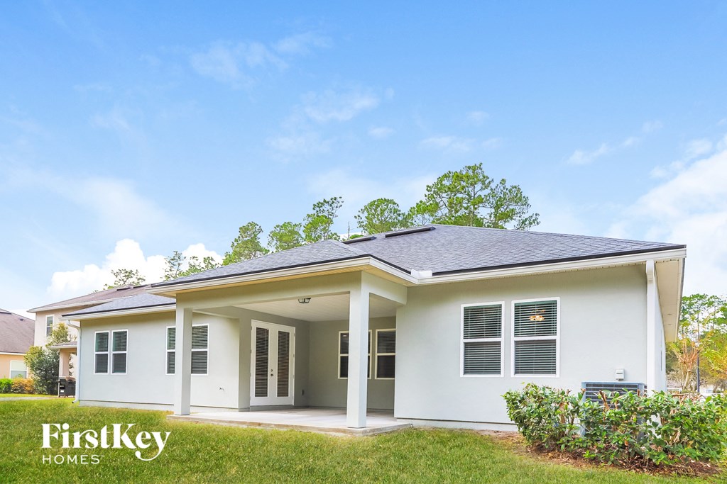 front view of a white house with a lawn and trees