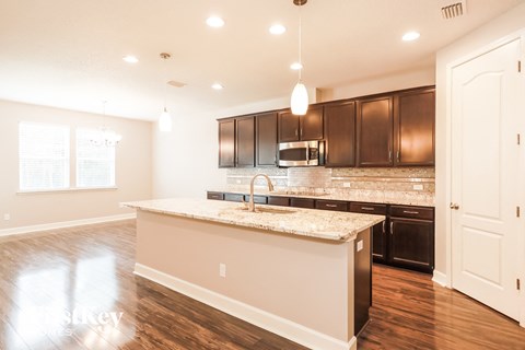 a kitchen with brown cabinets and a marble counter top