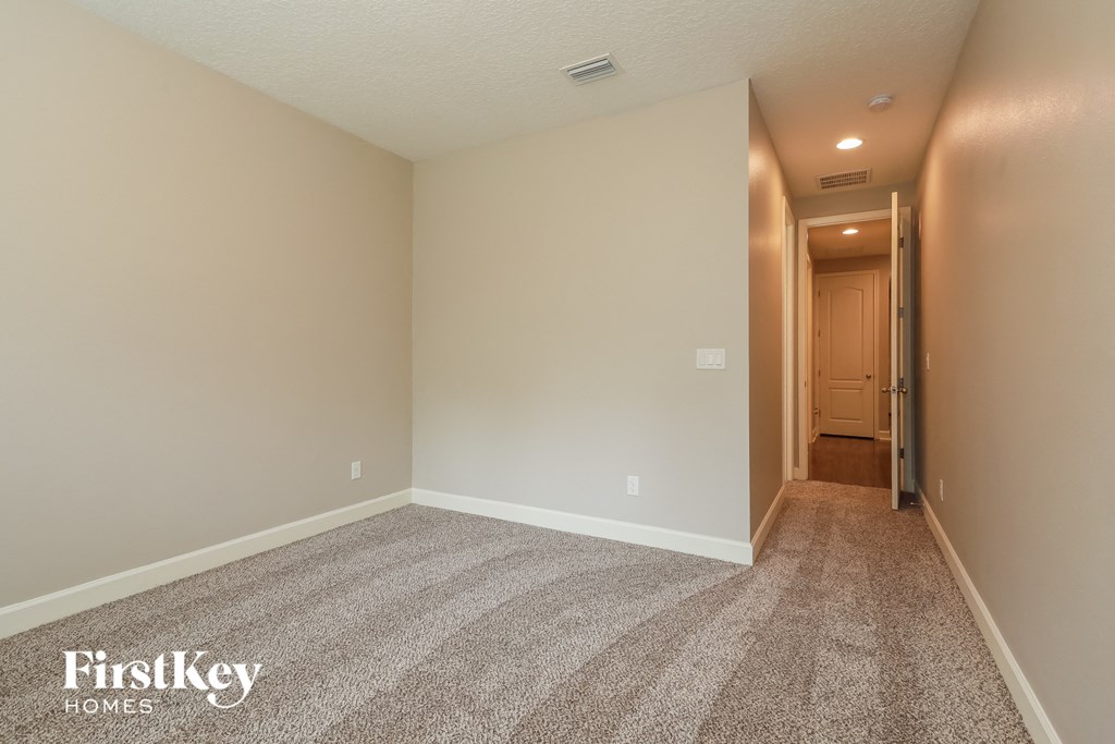 a bedroom with a carpeted floor and a hallway to a closet