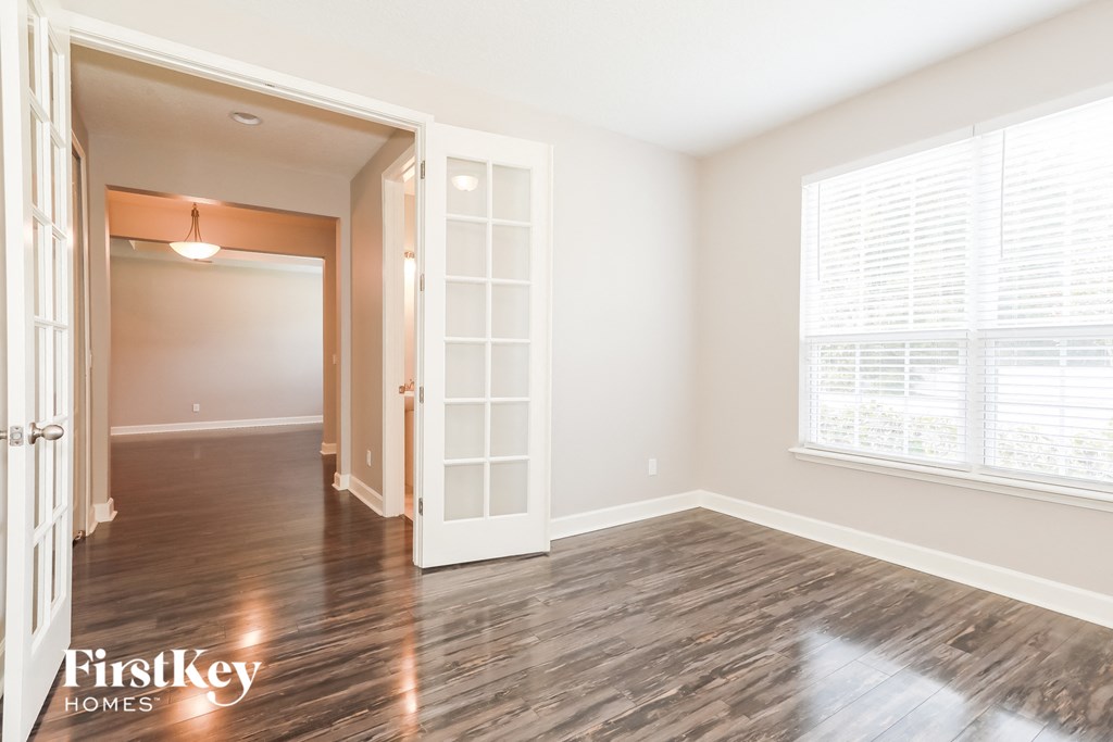 the living room and dining room of a house with wood floors and a white door