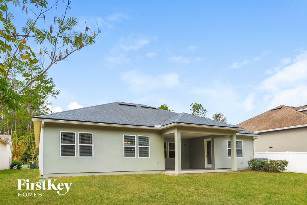 a white house with a lawn and a tree