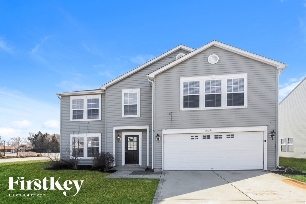A grey two-story house with a black front door and a white garage door.