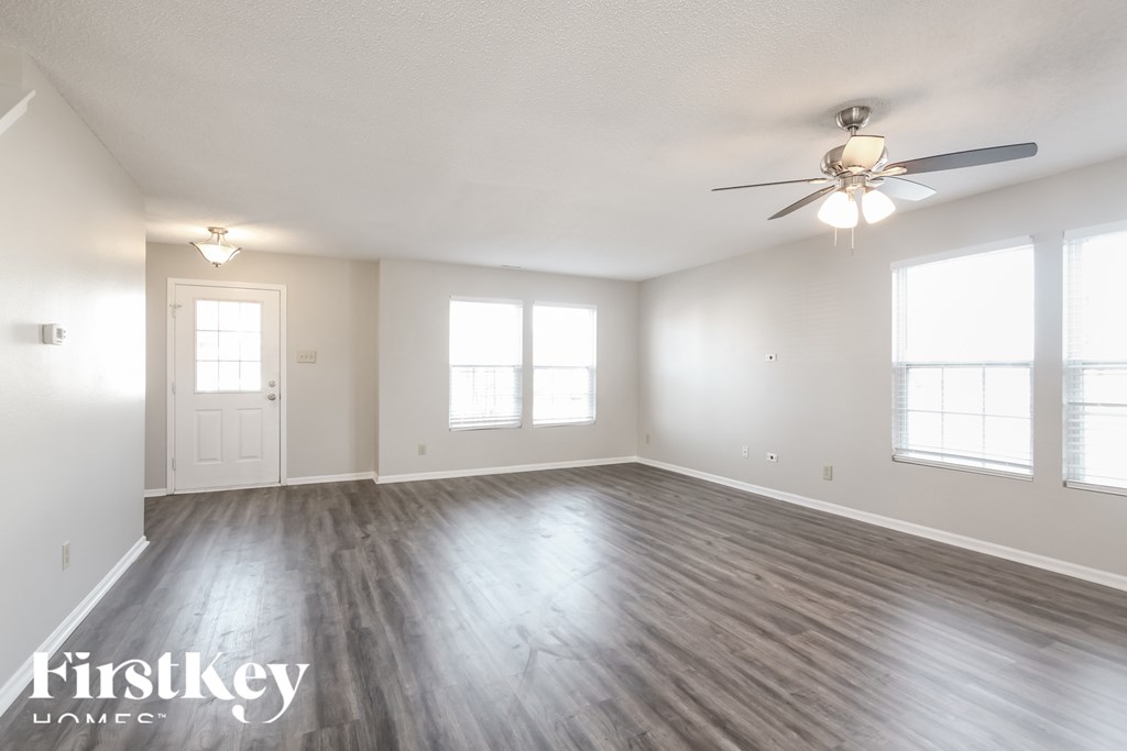 A spacious room with wooden floors and a ceiling fan.
