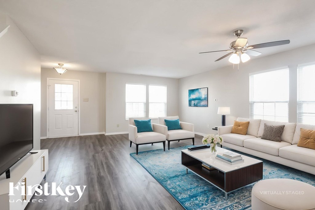 A living room with a white couch, a coffee table, and a ceiling fan.