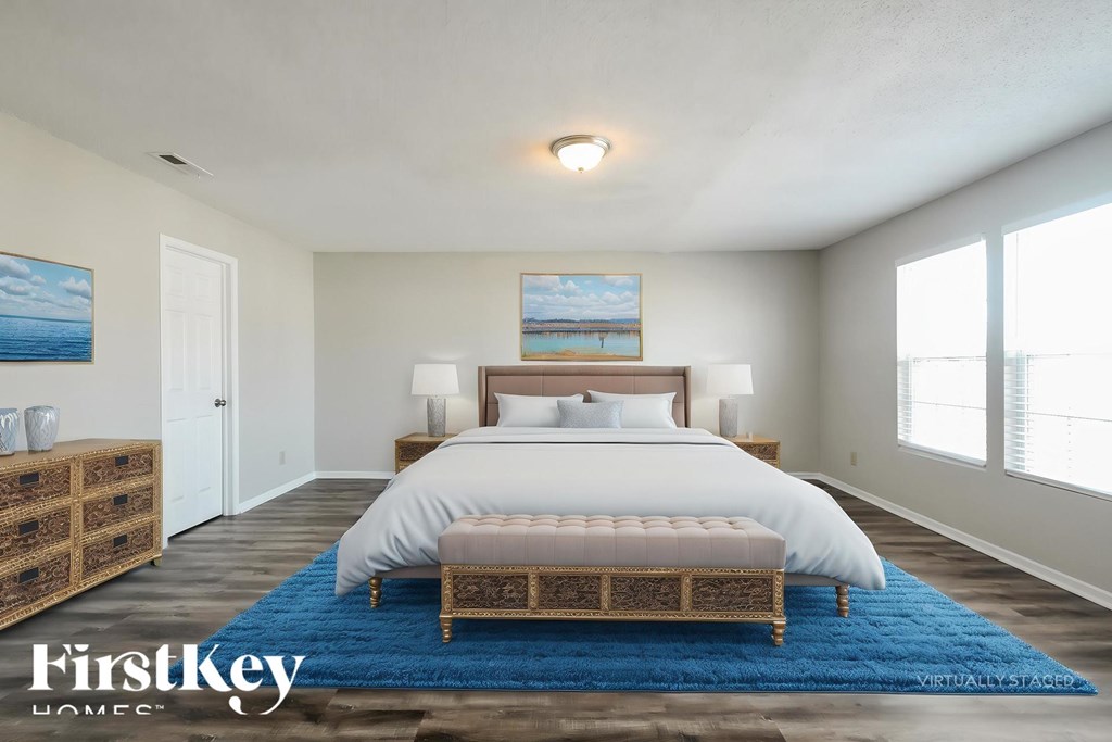 A bedroom with a large bed and a painting on the wall.