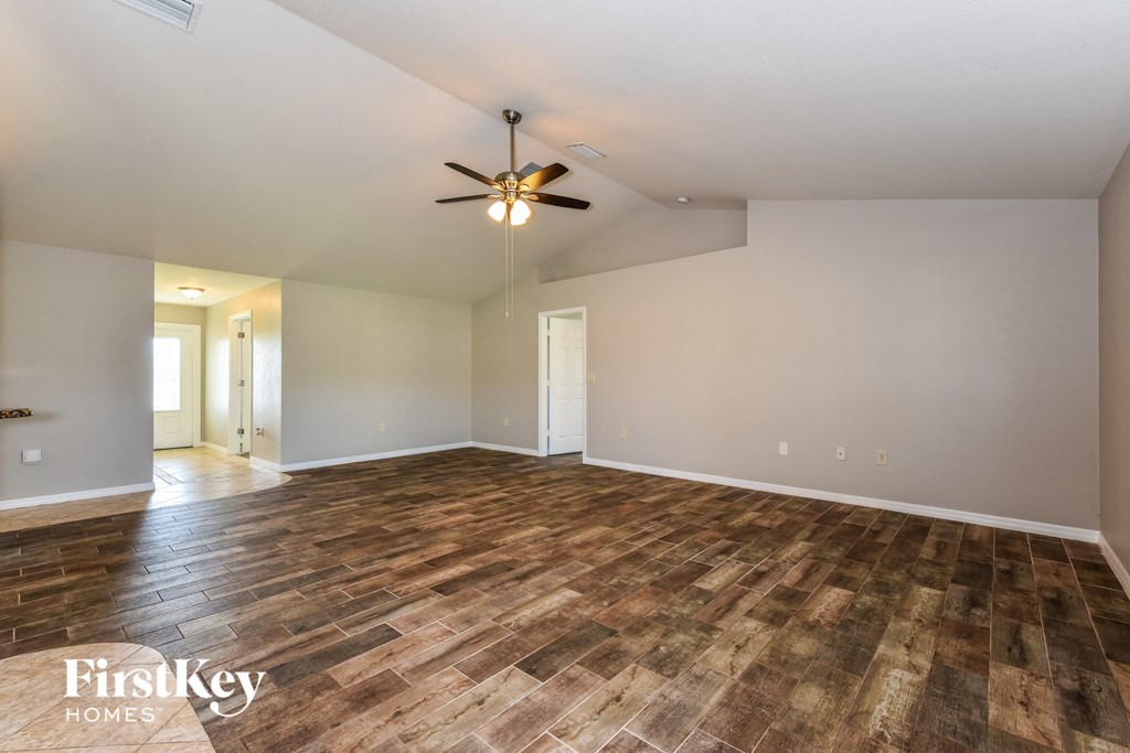 the living room with wood flooring and a ceiling fan
