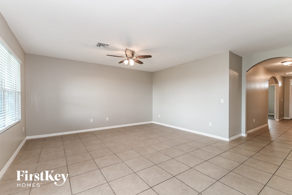 a empty living room with a ceiling fan and a tiled floor