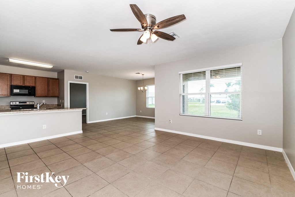 an empty kitchen and living room with a ceiling fan