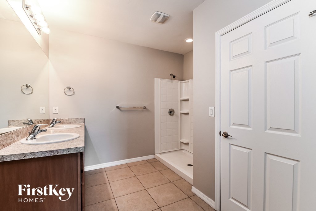 a bathroom with a sink and a shower and a white door