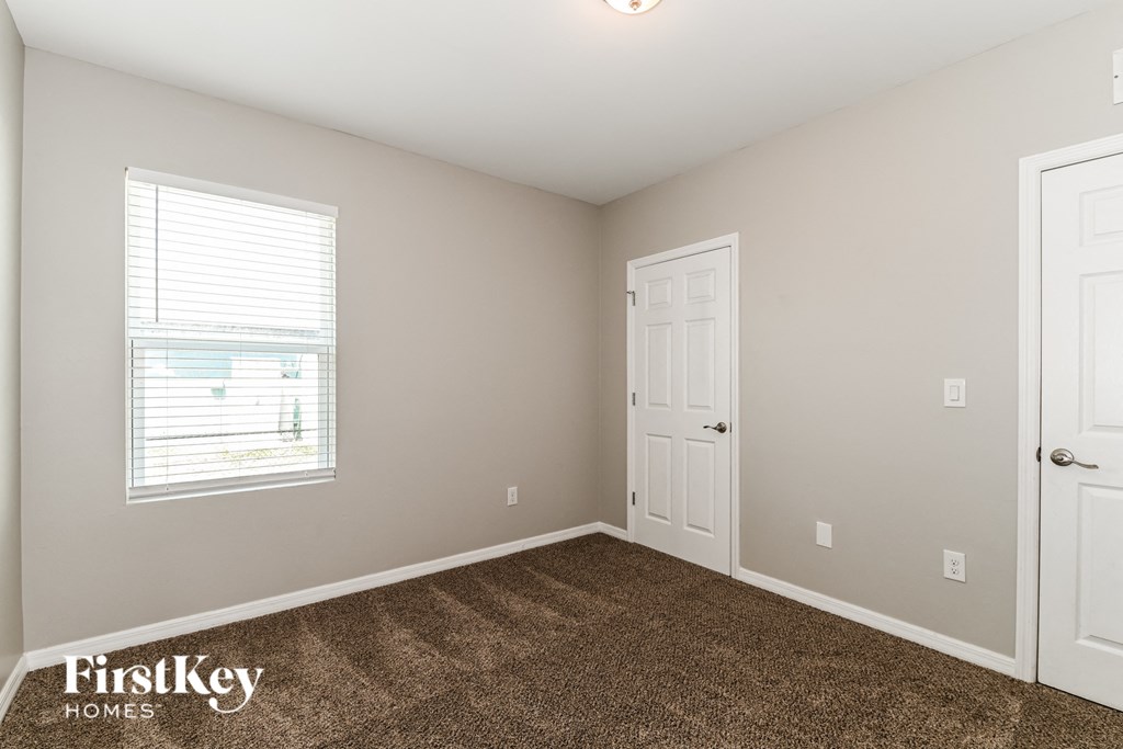 a bedroom with carpet and a door and a window