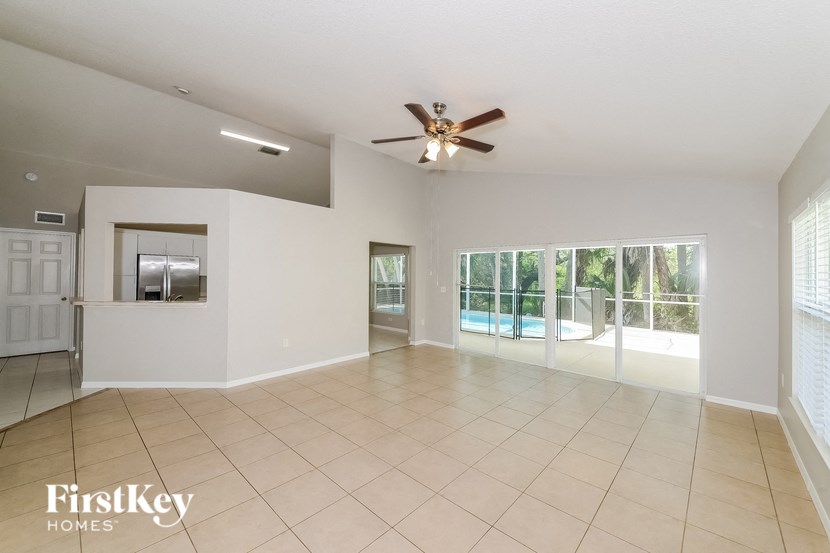 A spacious room with a ceiling fan and sliding glass doors leading to a balcony.