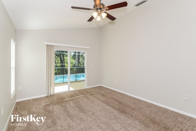 A room with a carpet floor and a ceiling fan.