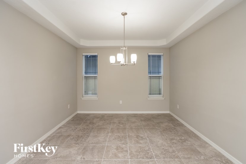 A spacious room with a tile floor and a chandelier hanging from the ceiling.