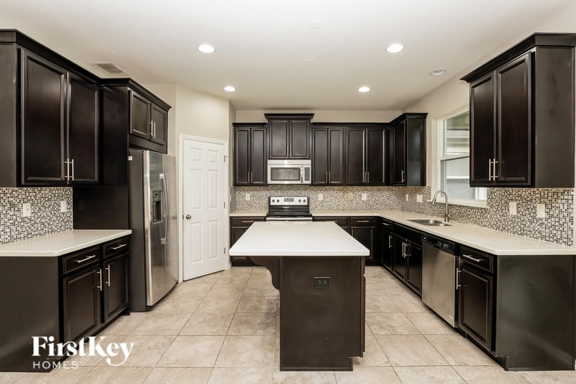 A kitchen with dark brown cabinets and a white island.