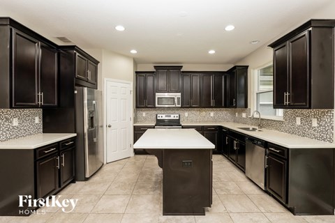 A kitchen with dark brown cabinets and a white island.