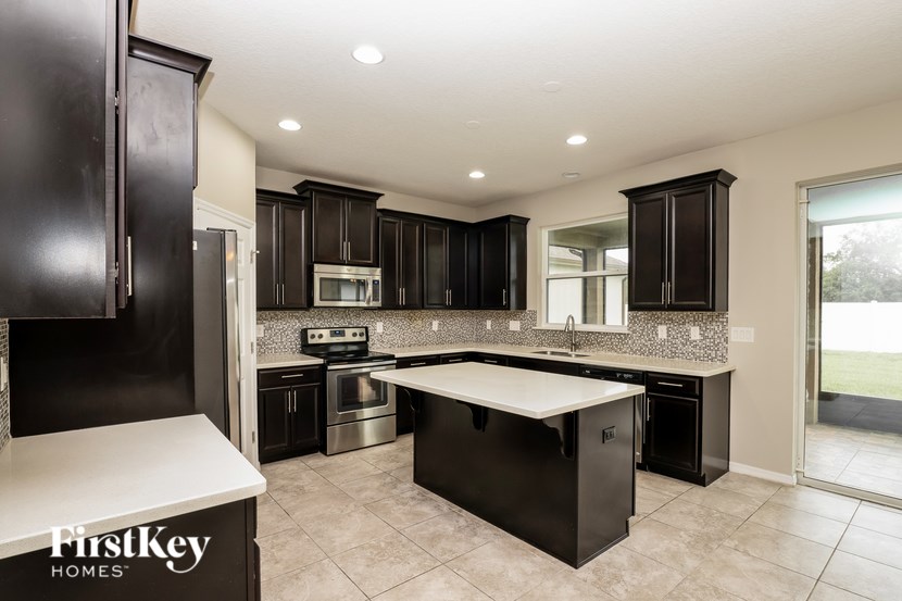 A kitchen with black cabinets and a white island.
