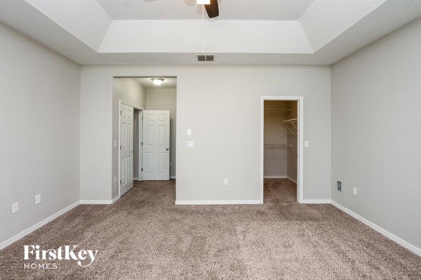 A spacious room with carpeted flooring and two doors.