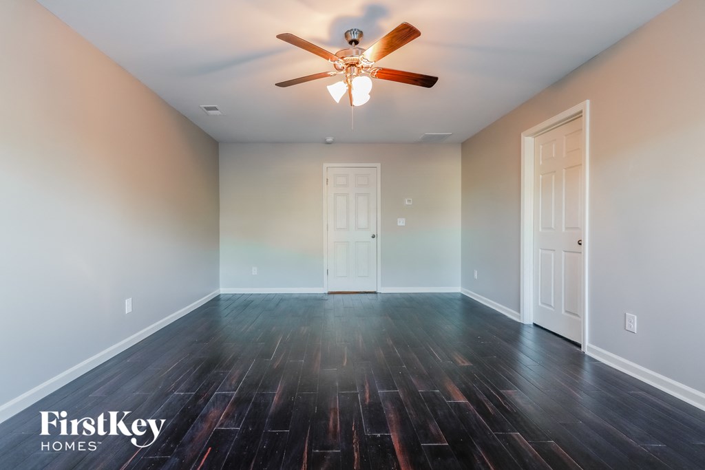 a empty living room with wood floors and a ceiling fan