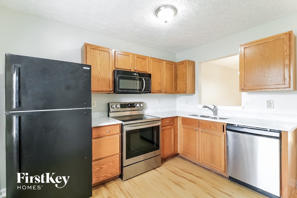 A kitchen with wooden cabinets and a black fridge.