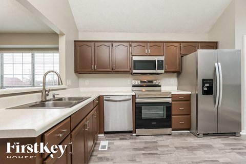 A kitchen with brown cabinets and a stainless steel refrigerator.