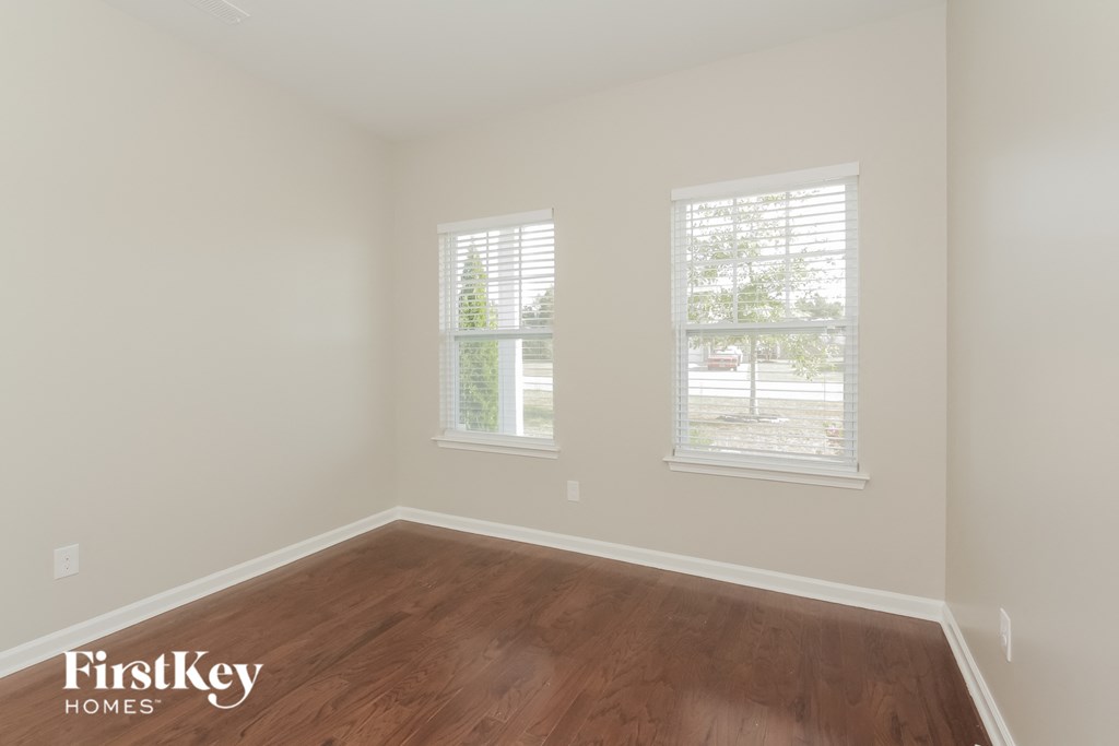 a empty room with a wooden floor and two windows