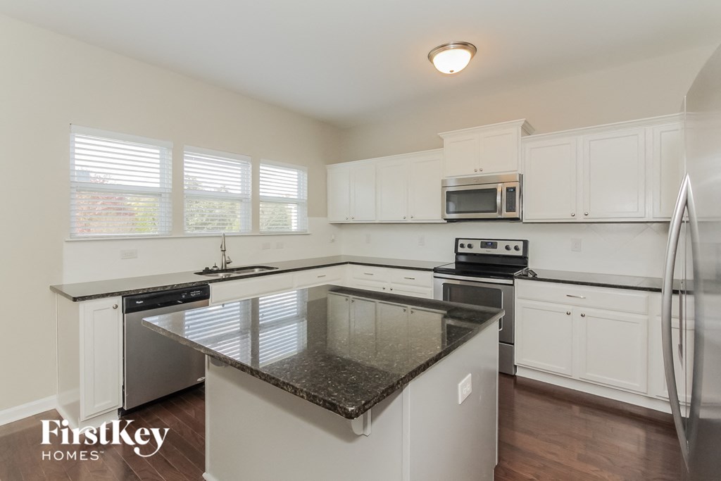 a kitchen with white cabinets and a black counter top