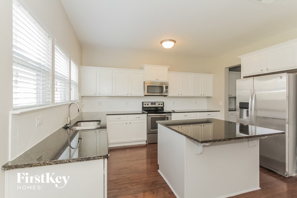 a kitchen with white cabinets and granite counter tops and stainless steel appliances