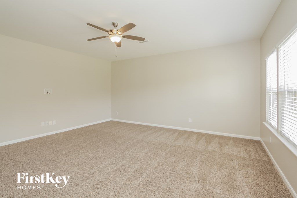 an empty living room with a ceiling fan and window