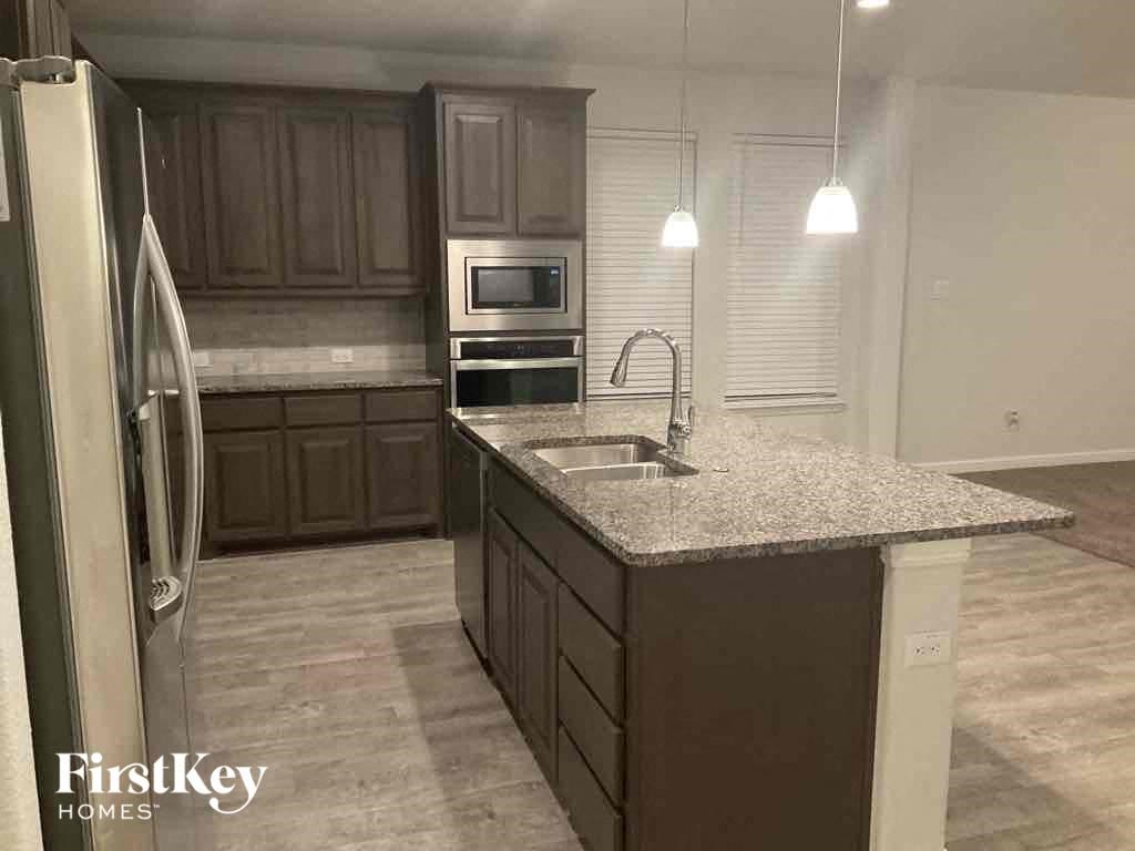 A kitchen with a granite countertop and wooden cabinets.