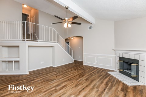 A spacious living room with a fireplace and a staircase.