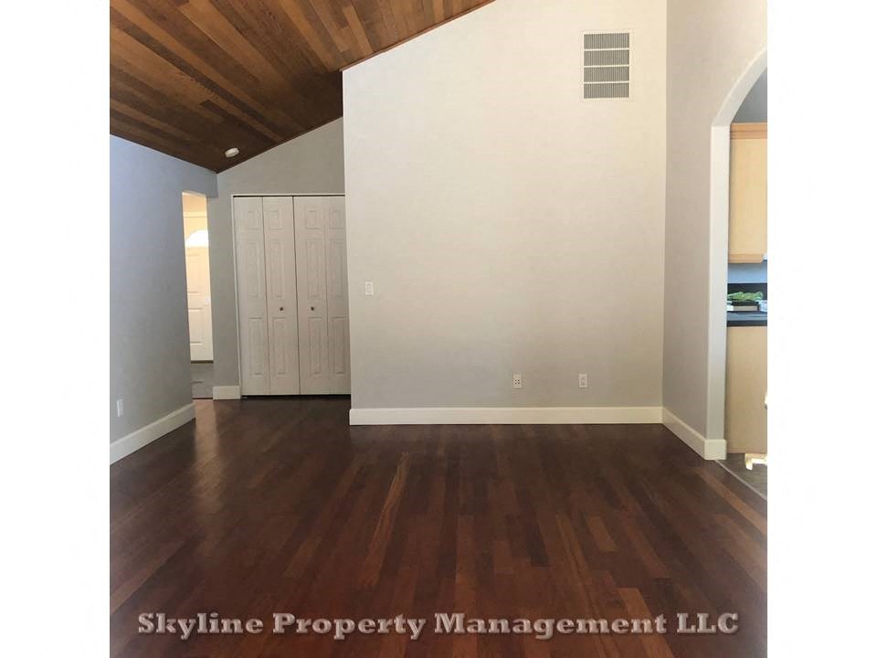 an empty living room with wood floors and white walls