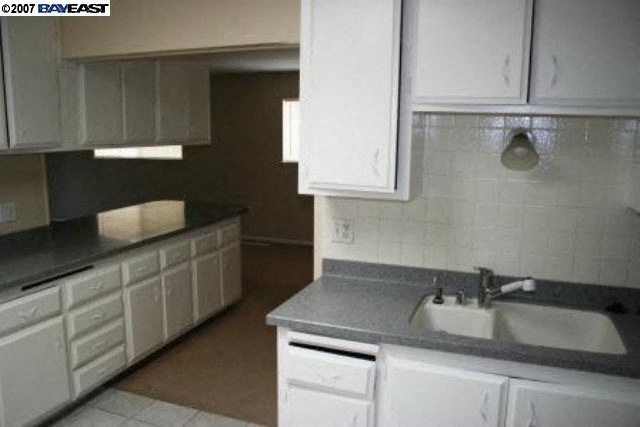 A kitchen with white cabinets and a sink.