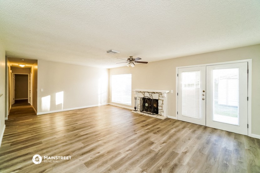 an empty living room with a fireplace and a ceiling fan