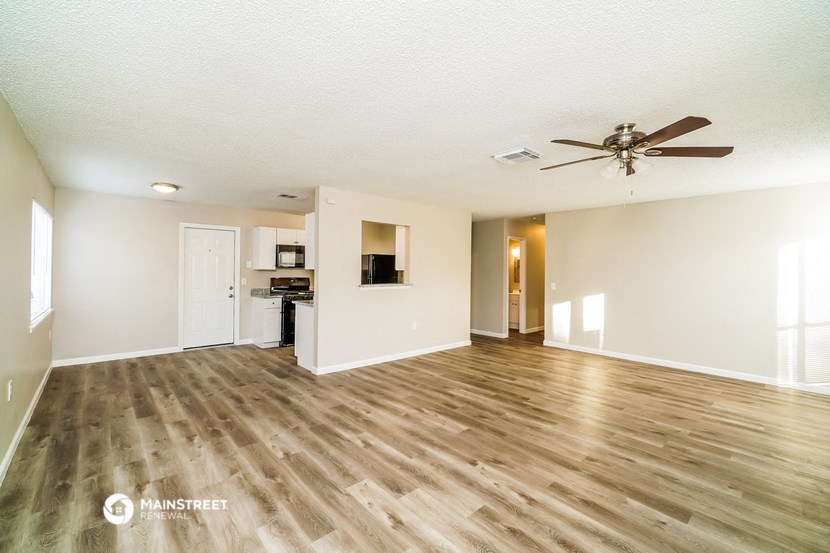 an empty living room with hardwood floors and a ceiling fan