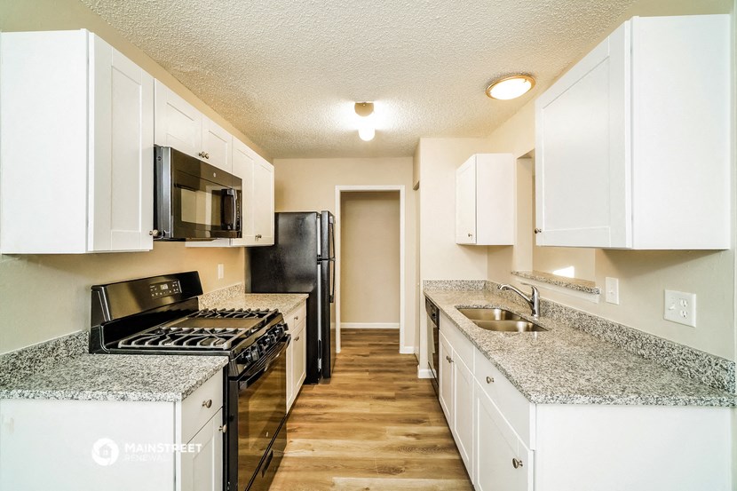an empty kitchen with white cabinets and granite counter tops
