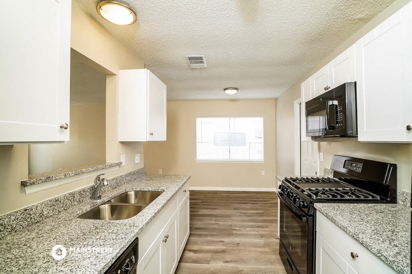 an empty kitchen with granite counter tops and white cabinets
