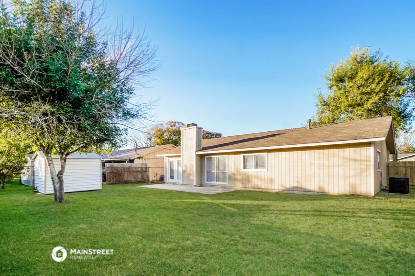 a backyard with a wooden house and a yard with a tree