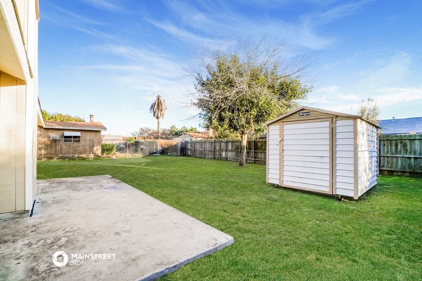 a small shed in the backyard of a house with a yard and a fence
