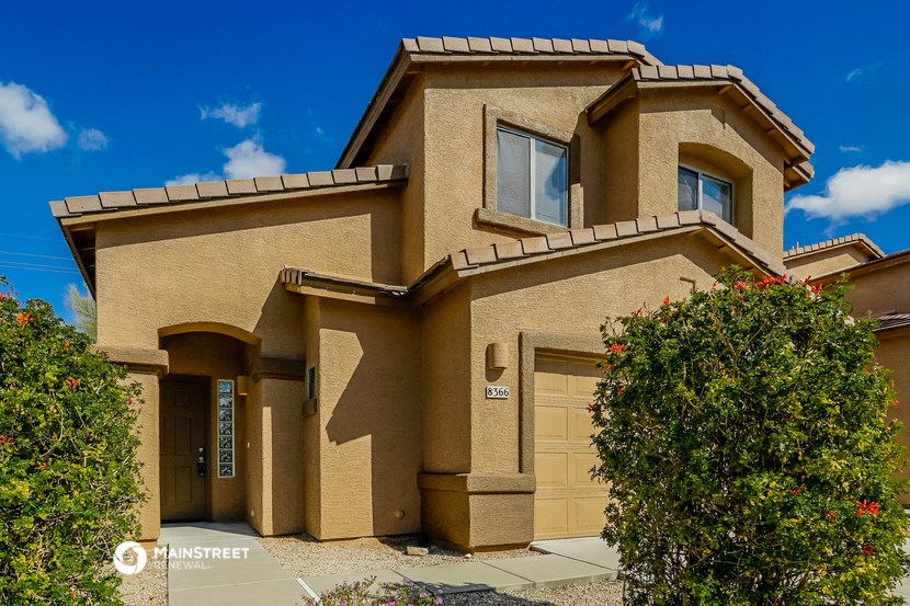 a tan house with two garage doors and a driveway