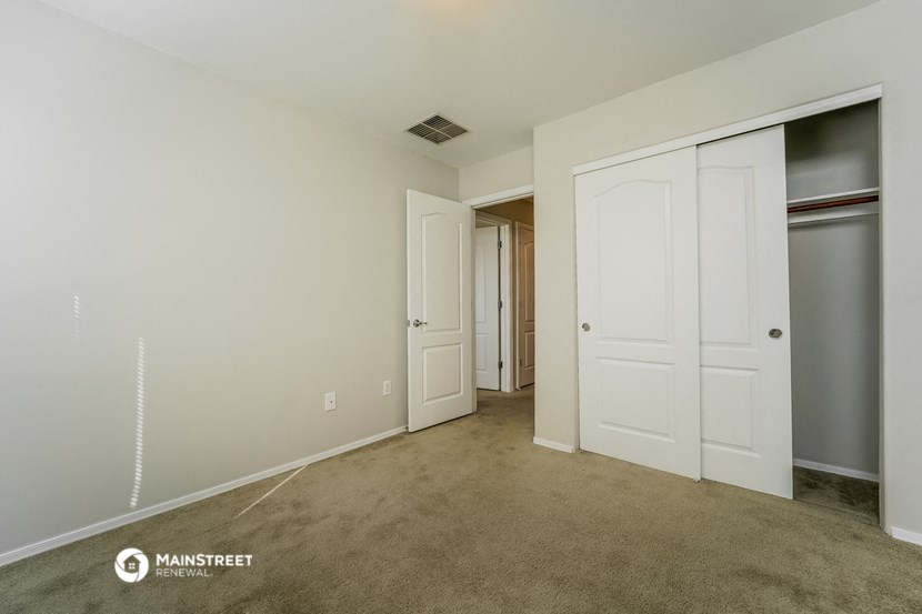 a bedroom with two closets and a carpeted floor and a hallway with doors