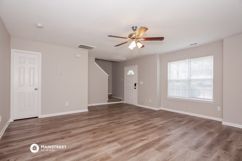 the spacious living room with ceiling fan and hardwood floors