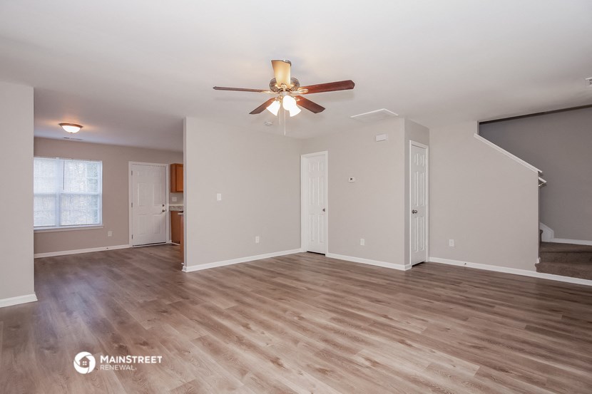 the living room of an empty house with a ceiling fan