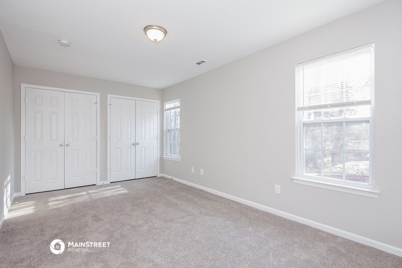 a bedroom with two closets and a carpeted floor