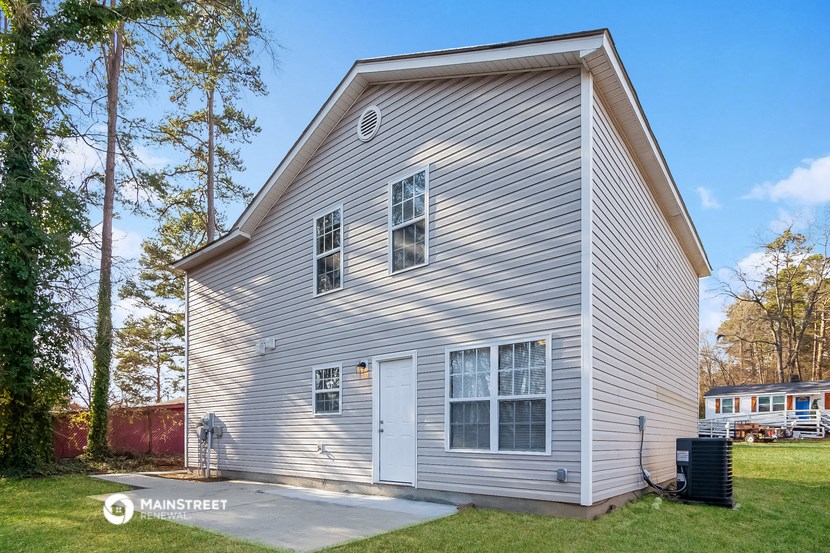 the outside of a white house with a garage and trees