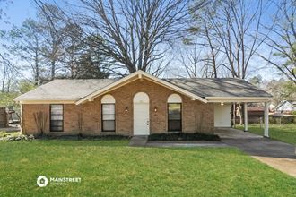 the front of a brick house with white doors and a driveway