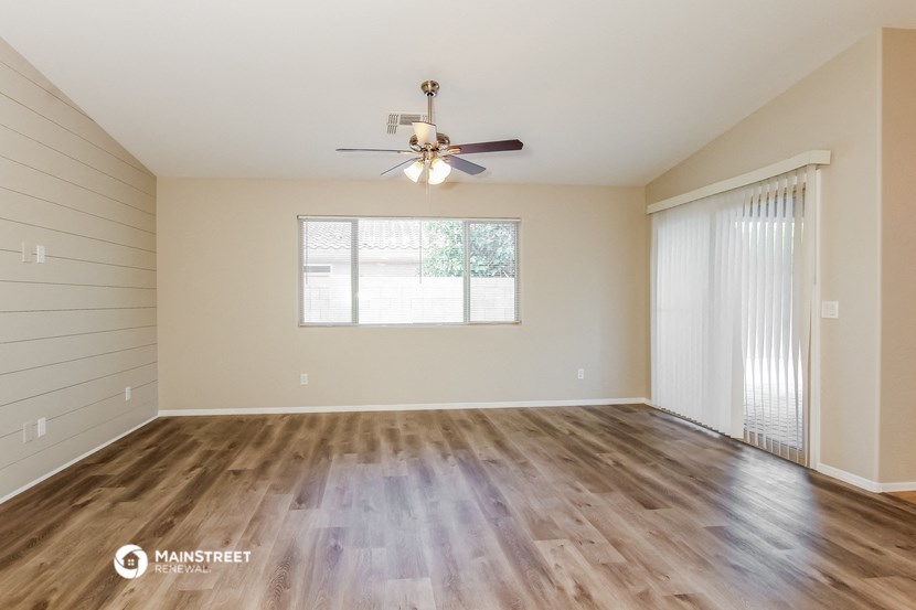 the spacious living room with hardwood floors and a ceiling fan