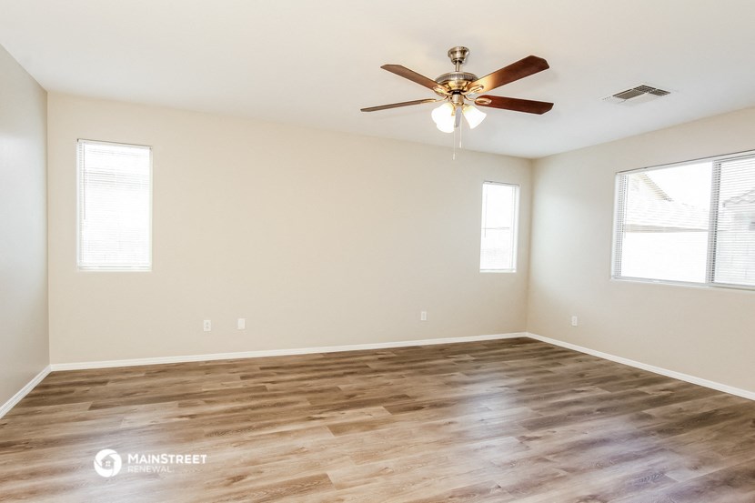 the spacious living room with hardwood floors and a ceiling fan