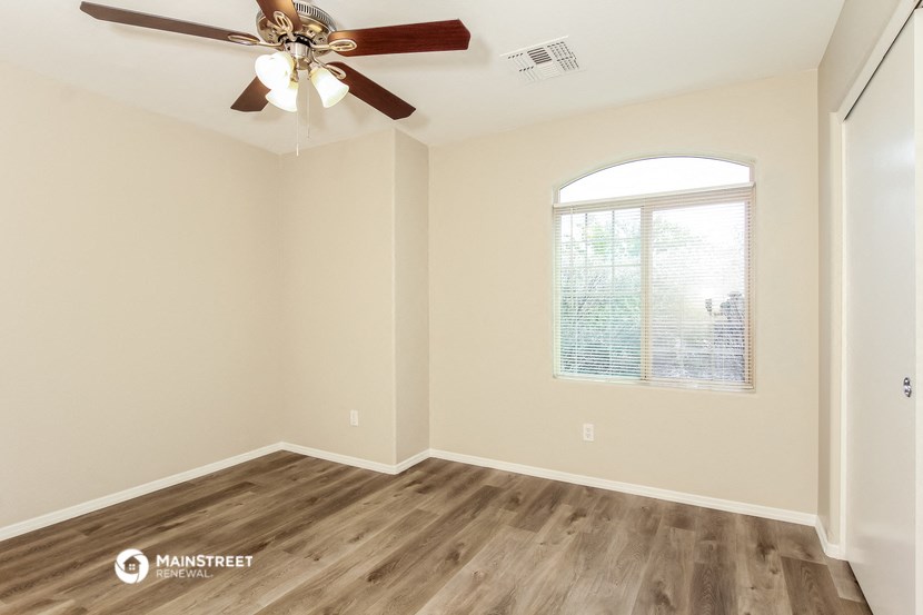the spacious living room with a ceiling fan and wood flooring