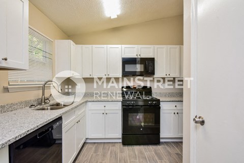 a kitchen with white cabinets and a black stove and a microwave