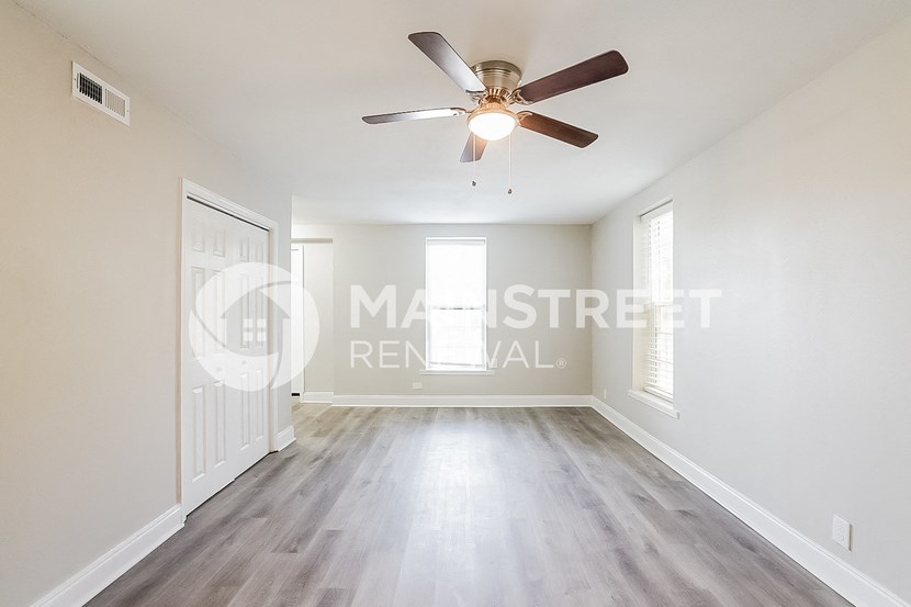 a living room with white walls and a ceiling fan